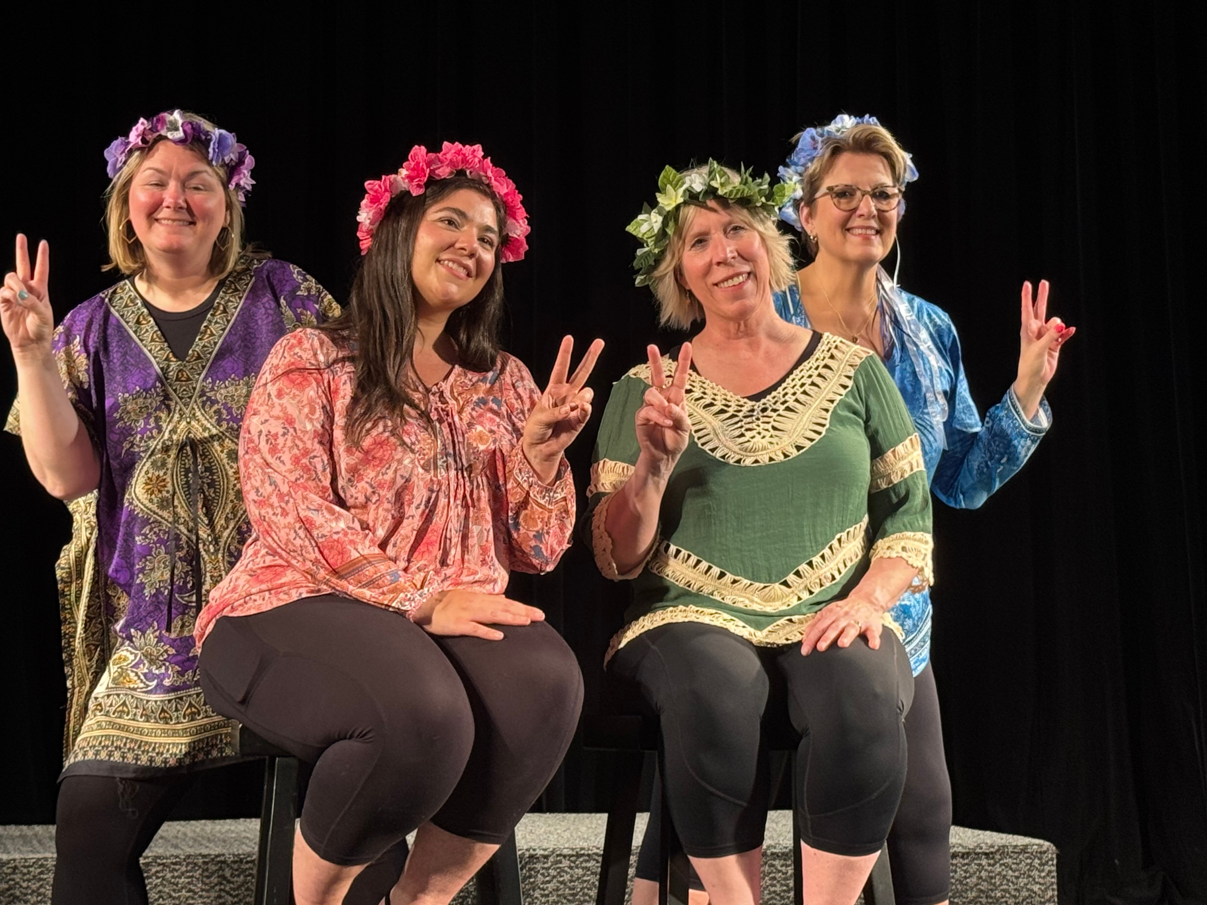 Four performers in colorful costumes and flower crowns on stage