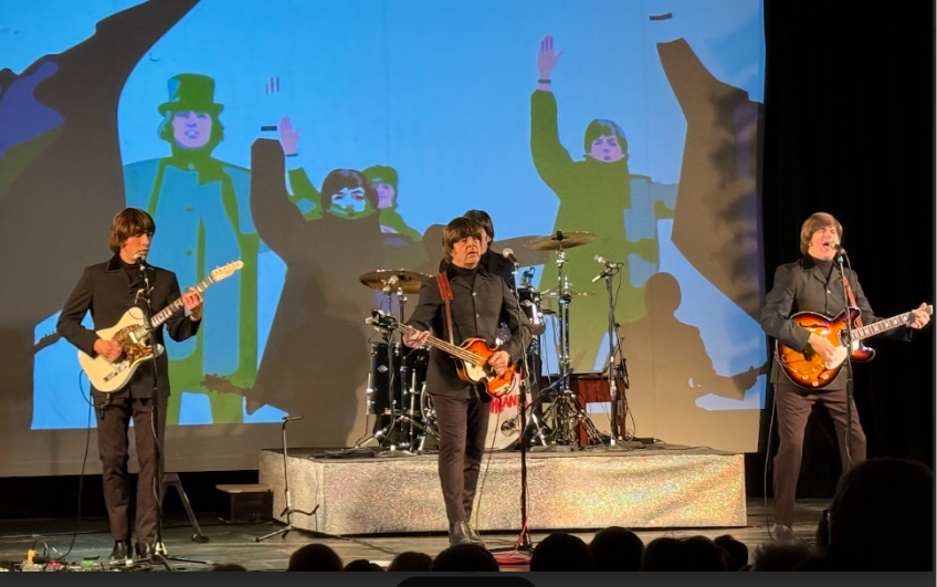 Beatles tribute band performing on stage with animated backdrop