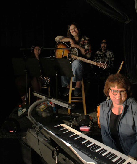 Musicians performing on stage with a keyboard in the foreground