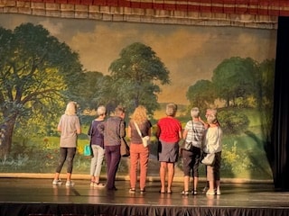 Group standing before the theatre pastoral stage backdrop